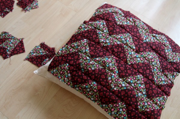 checking the size of the patchwork piece by placing it on top of the cushion
