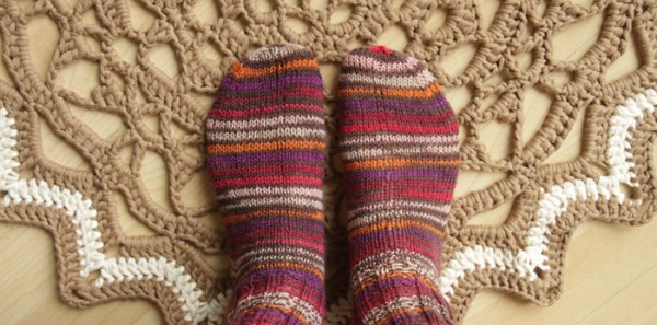Knitted socks on a crochet doily rug