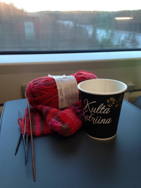 Ball of yarn and a coffee cup on a table by a train window