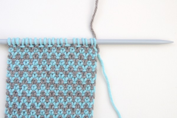 Step 3 - Give the yarns a small tug to create a neat edge. Tug the old (blue) yarn down, and the new (grey) yarn upwards, and then keep knitting.